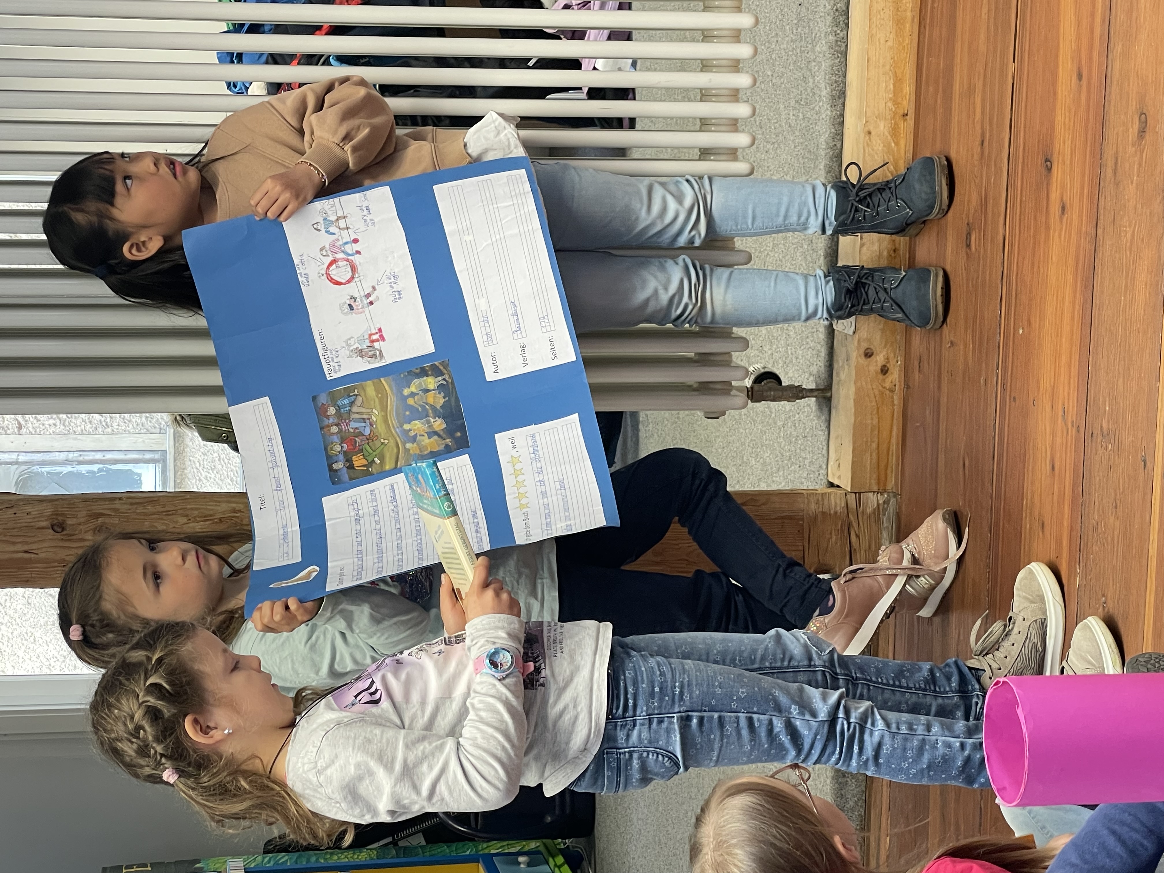 Drei kleine Kinder tragen mit einem Poster einen Vortrag vor